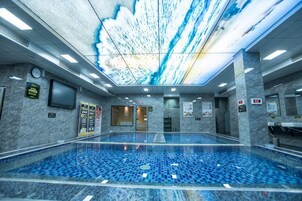 Una amplia piscina interior con proyección en el techo, un área de recepción y vistas despejadas a la piscina.