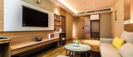 A modern living room with a flat-screen TV, wooden furniture, a round coffee table, and a sofa with a yellow pillow.