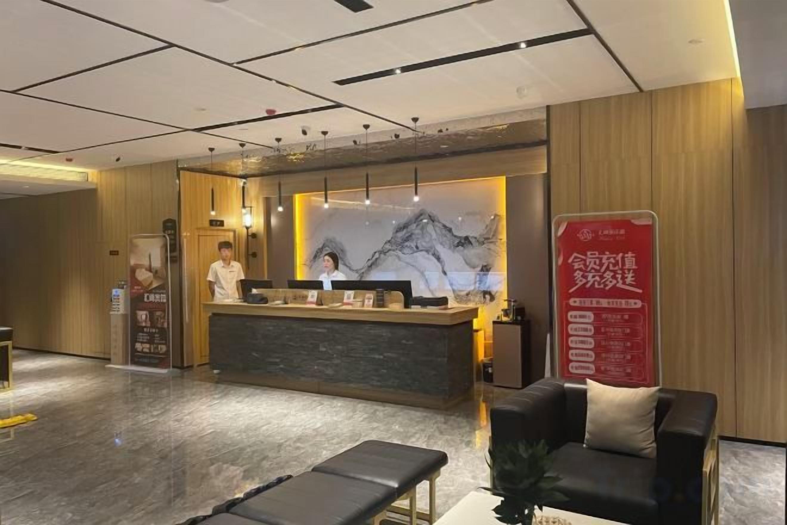 A hotel reception area with a reception desk, a waiting area with a sofa and bench, and a large poster on the wall.