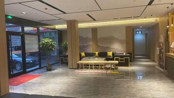 Un hall de hotel con mostrador de recepción, zona de estar y vistas al estacionamiento.