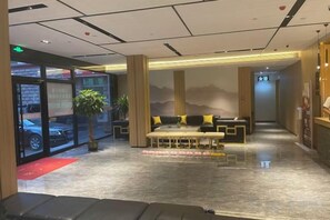 A hotel lobby with a reception desk, seating area, and a view of the parking area. - Huifeng Hotel (Longkou)