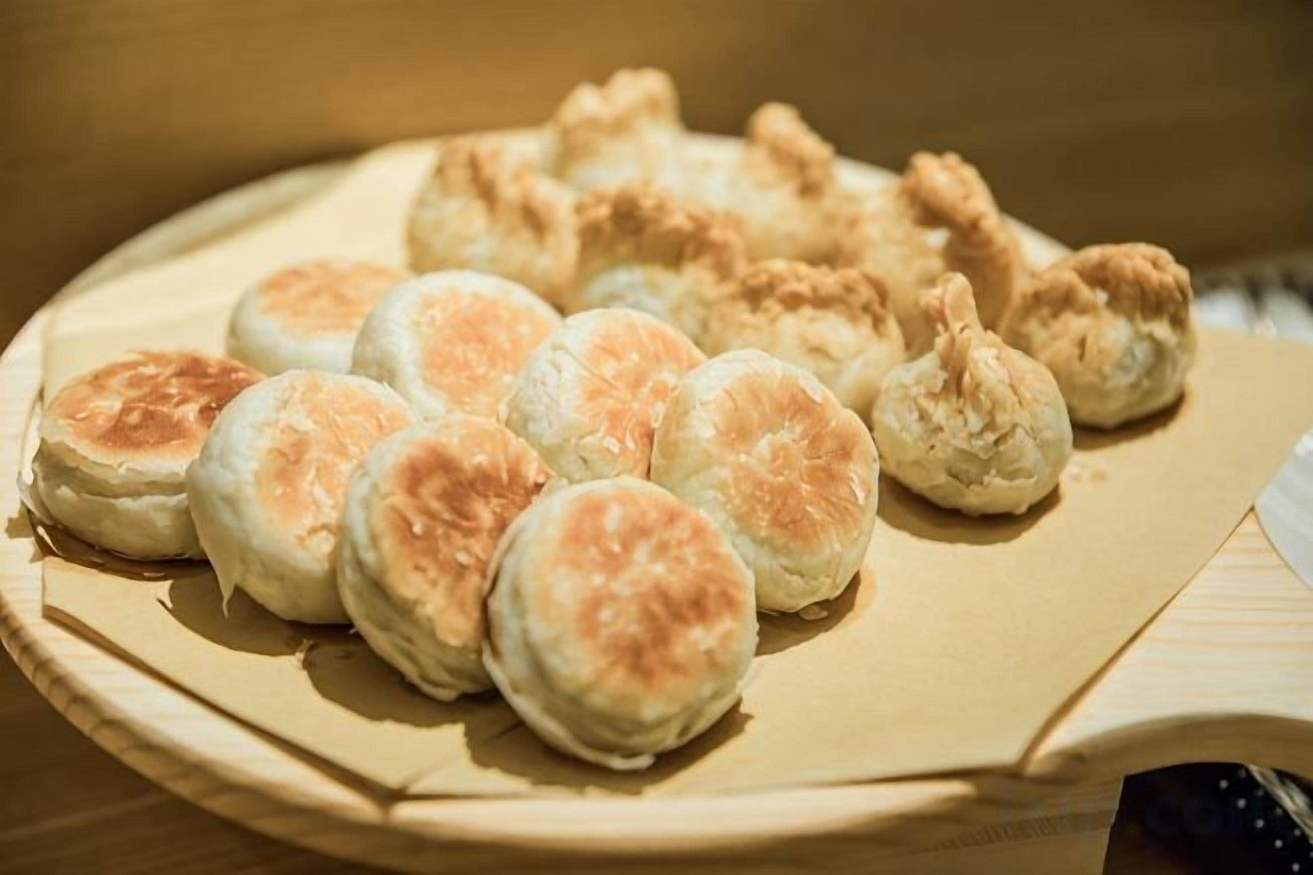 A plate of food items, including biscuits and possibly fried items, on a wooden surface.