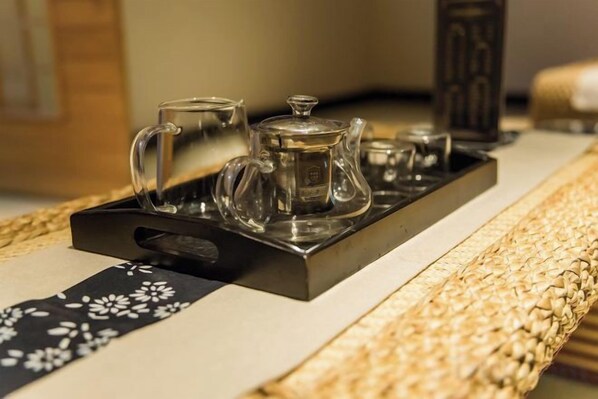A tray with a teapot, a glass, and a cup on a woven tablecloth. - Huifeng Hotel (Longkou)