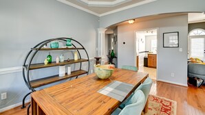 Un espace repas comprenant une table en bois, des chaises et une étagère incurvée.