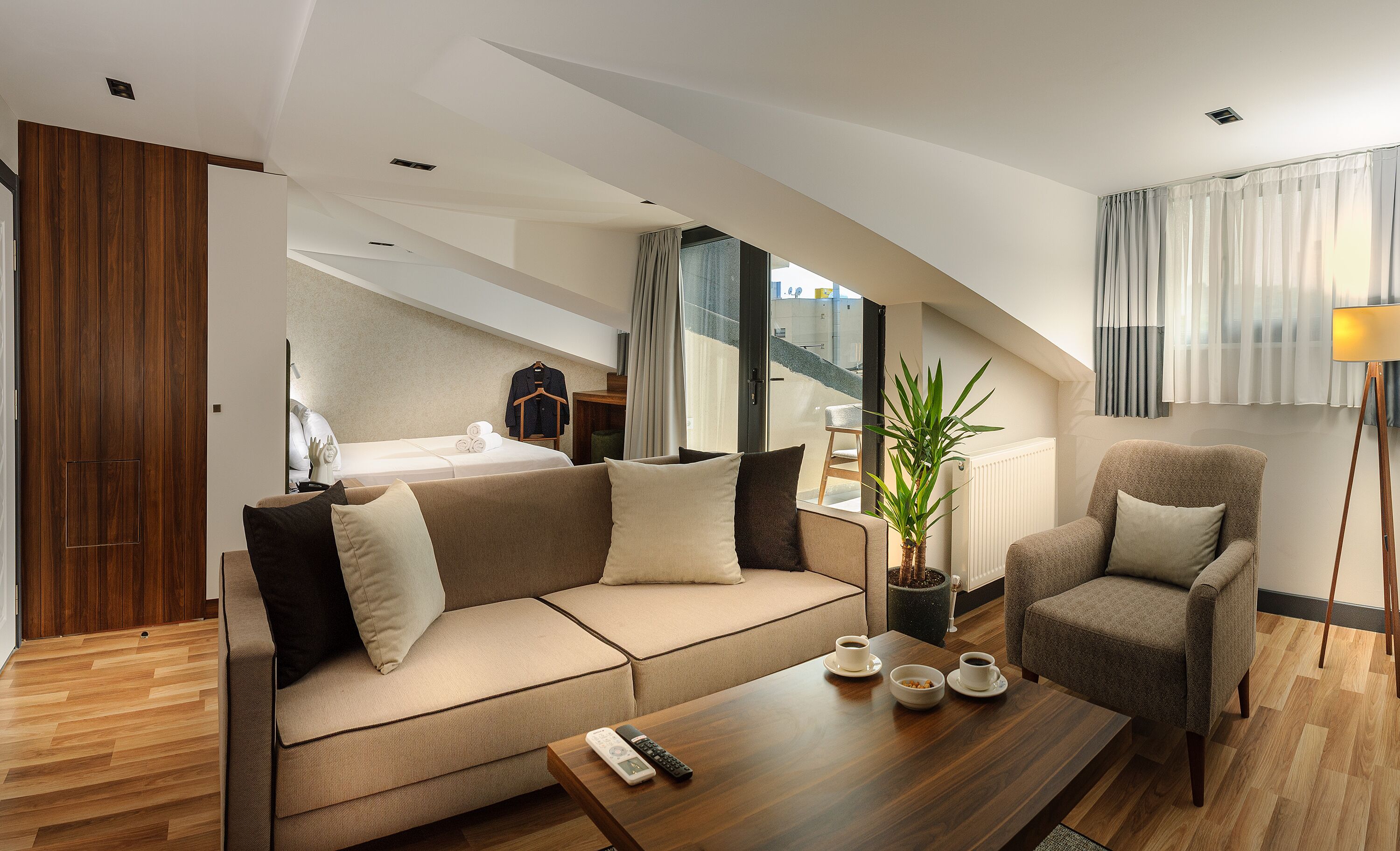 Une chambre d’hôtel moderne équipée d’un canapé, d’un fauteuil et d’une table à manger, ainsi que de télécommandes et de tasses.