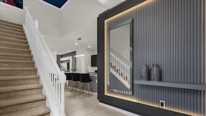 Ein modernes Interieur mit Treppe, Essbereich und Wand mit großem Spiegel und Dekoration.
