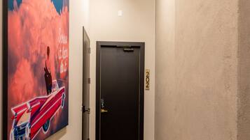 A hallway with a wooden floor, a black door, and a large poster on the wall.