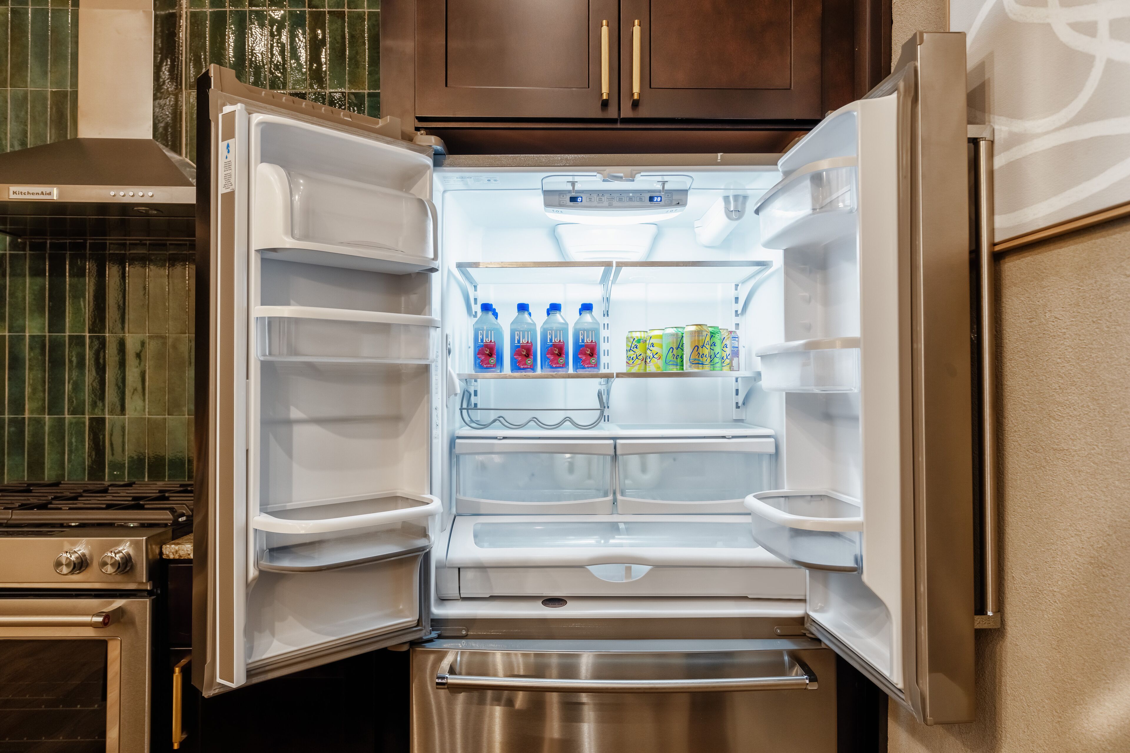 An open refrigerator with shelves containing beverages and a freezer compartment.