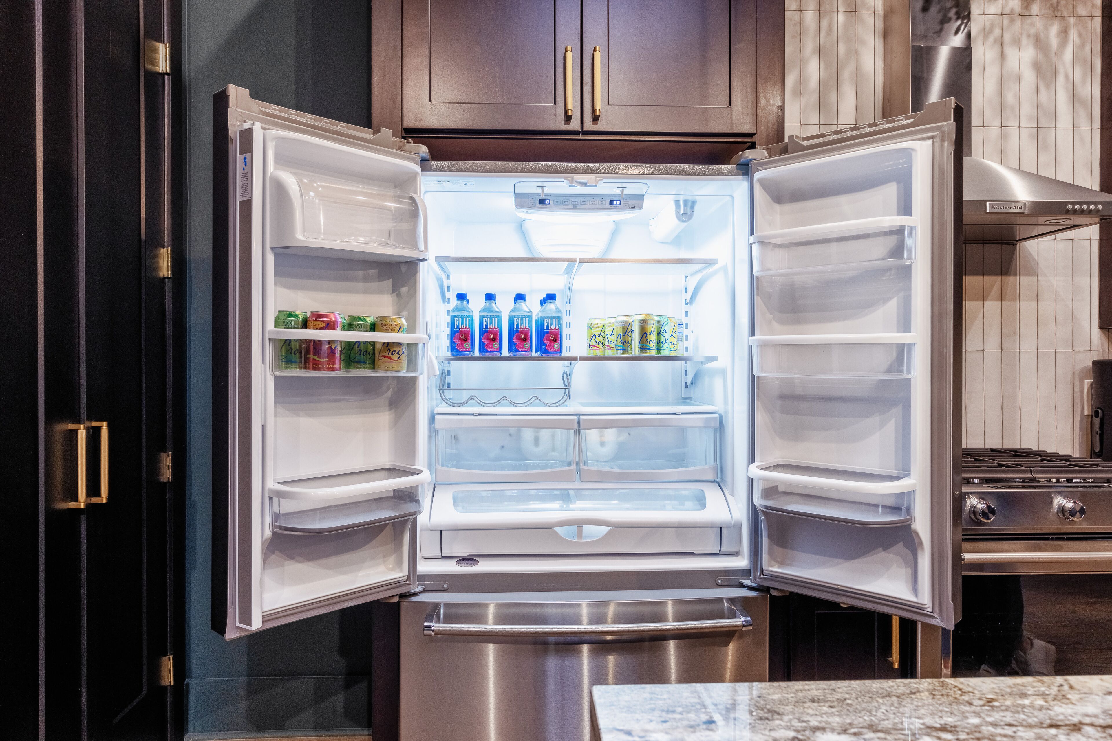 Un refrigerador abierto con estantes llenos de bebidas y alimentos enlatados.