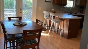 A kitchen with wooden cabinets, a dining table with chairs, and a bar area. - Home Away From Home (St. Augustine)