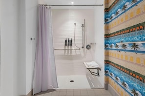 A bathroom with a shower, a towel rack, and a wall with a beach mural.