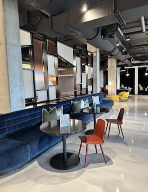 A modern lounge area with a blue sofa, round tables, and yellow chairs.