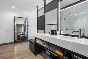 Une salle de bain moderne avec un grand miroir, un lavabo blanc et un porte-serviettes.