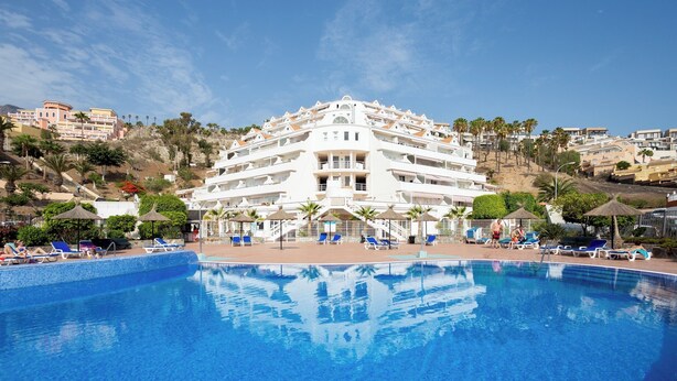 A large hotel with a swimming pool, multiple balconies, and a hillside view. - Home2Book Chill & Sun Colina Blanca & Pool, Adeje (Adeje)