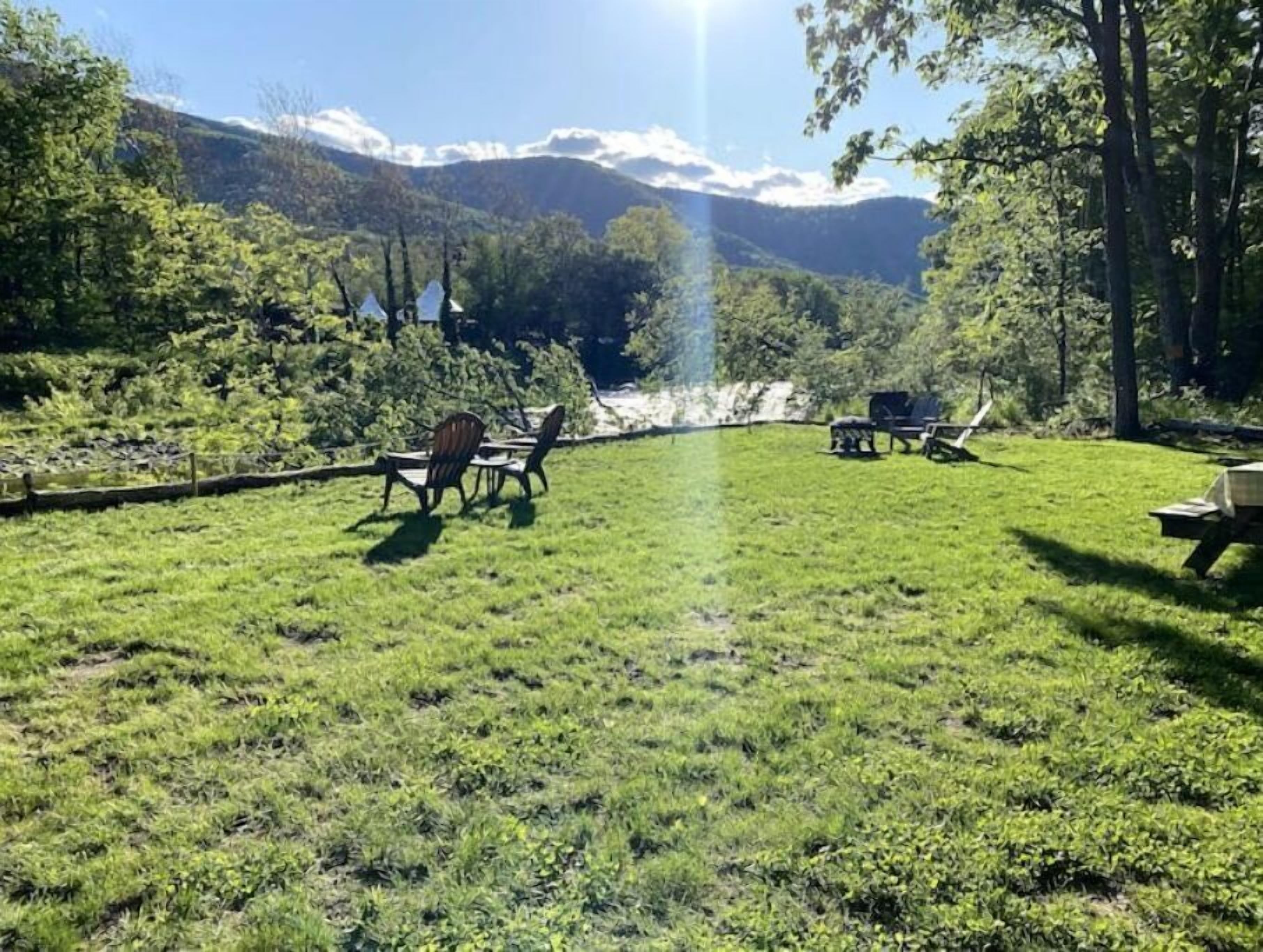 Spazio verde all'aperto con tavolo e sedie, barbecue e vista su una catena montuosa.