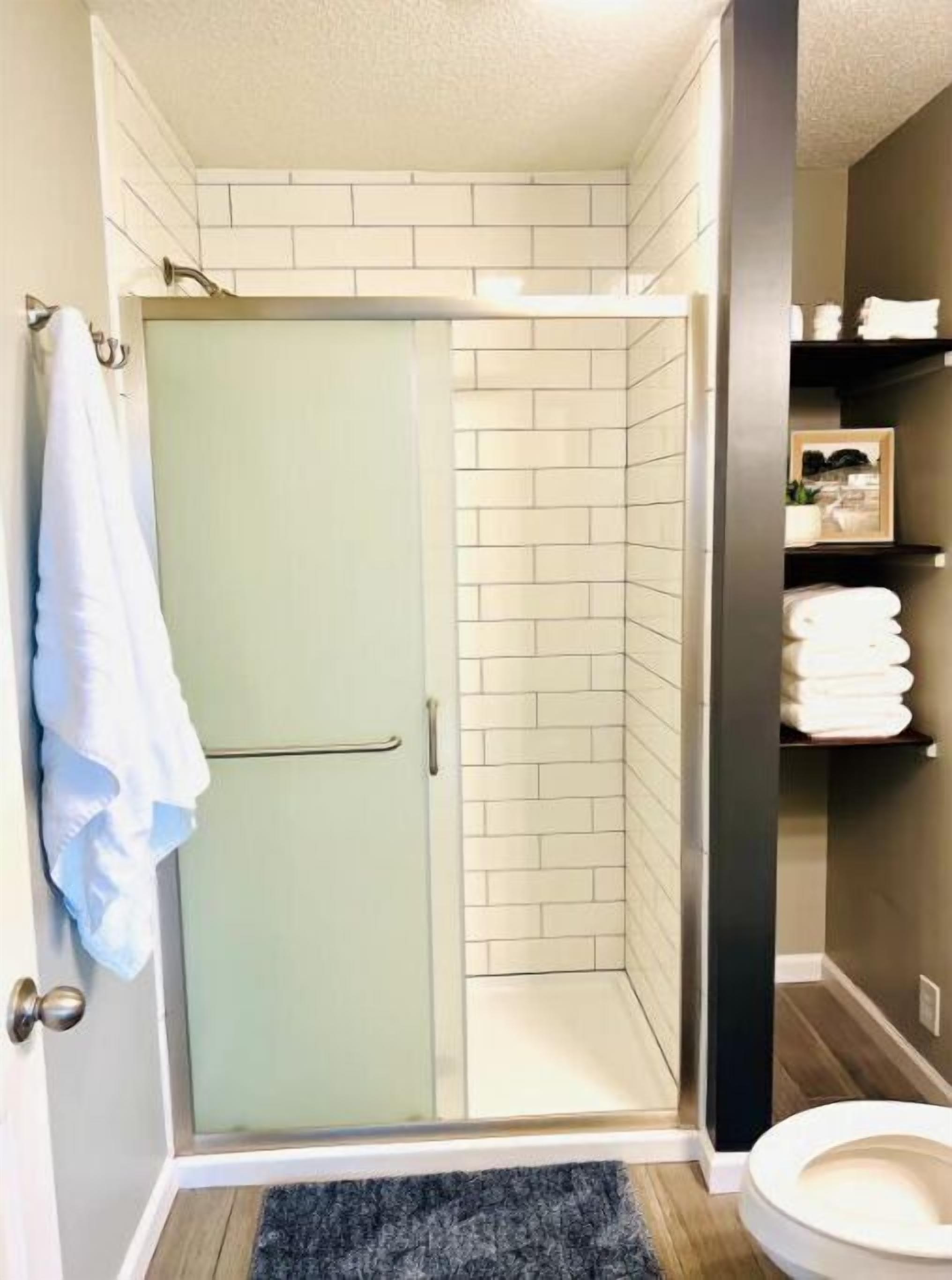 A bathroom with a shower, a toilet, and a towel rack.