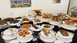 Un bufé con diversas opciones de pastelería y postres, como cruasanes, muffins y pasteles.