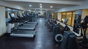 Un gimnasio con cintas de correr, elípticas y equipo de pesas.