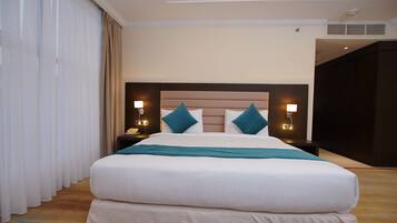 A hotel room with a large bed, two bedside tables with lamps, a headboard, and a view of the outside through the window.