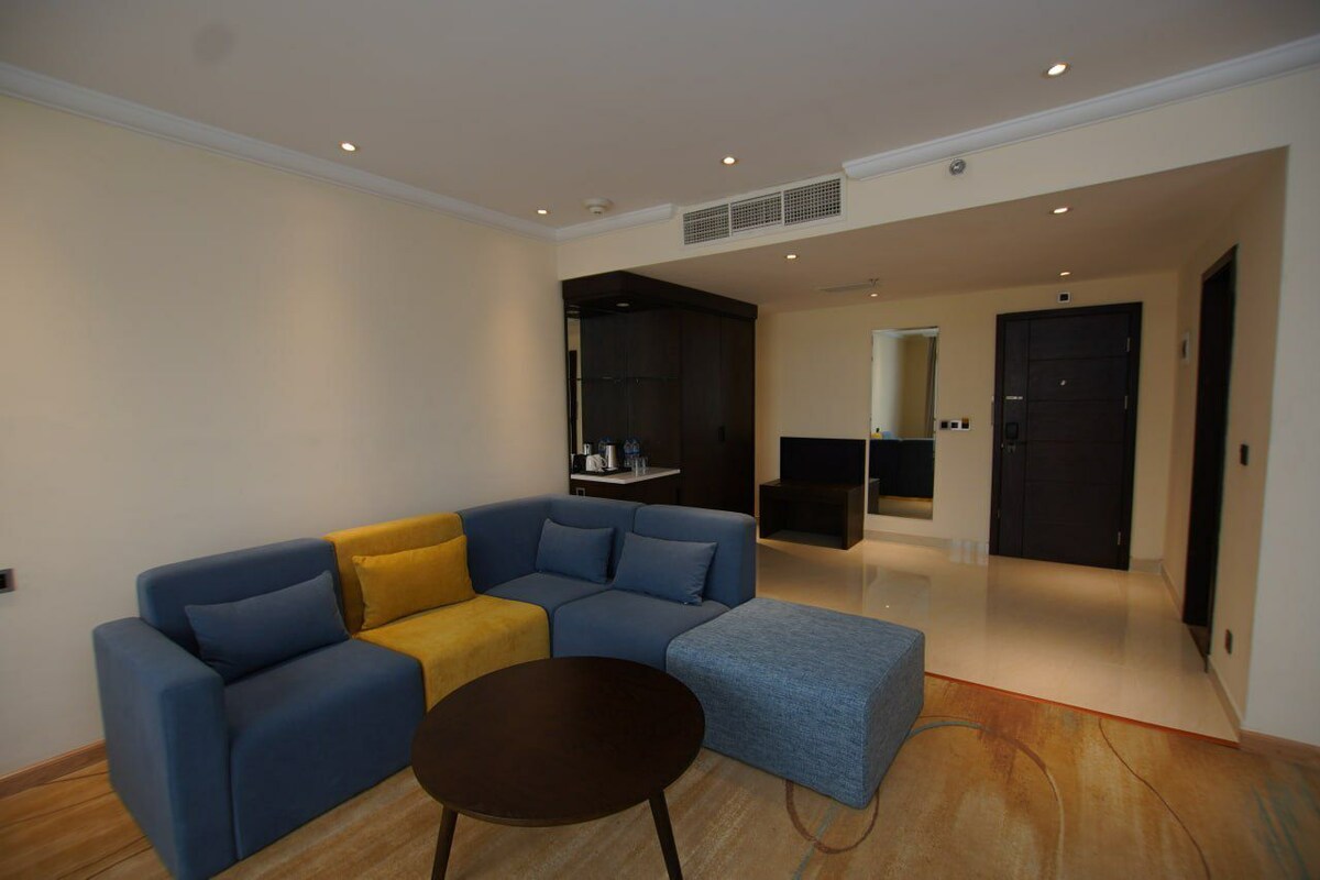 A modern living room with a sectional sofa, a small round table, and a built-in entertainment unit.