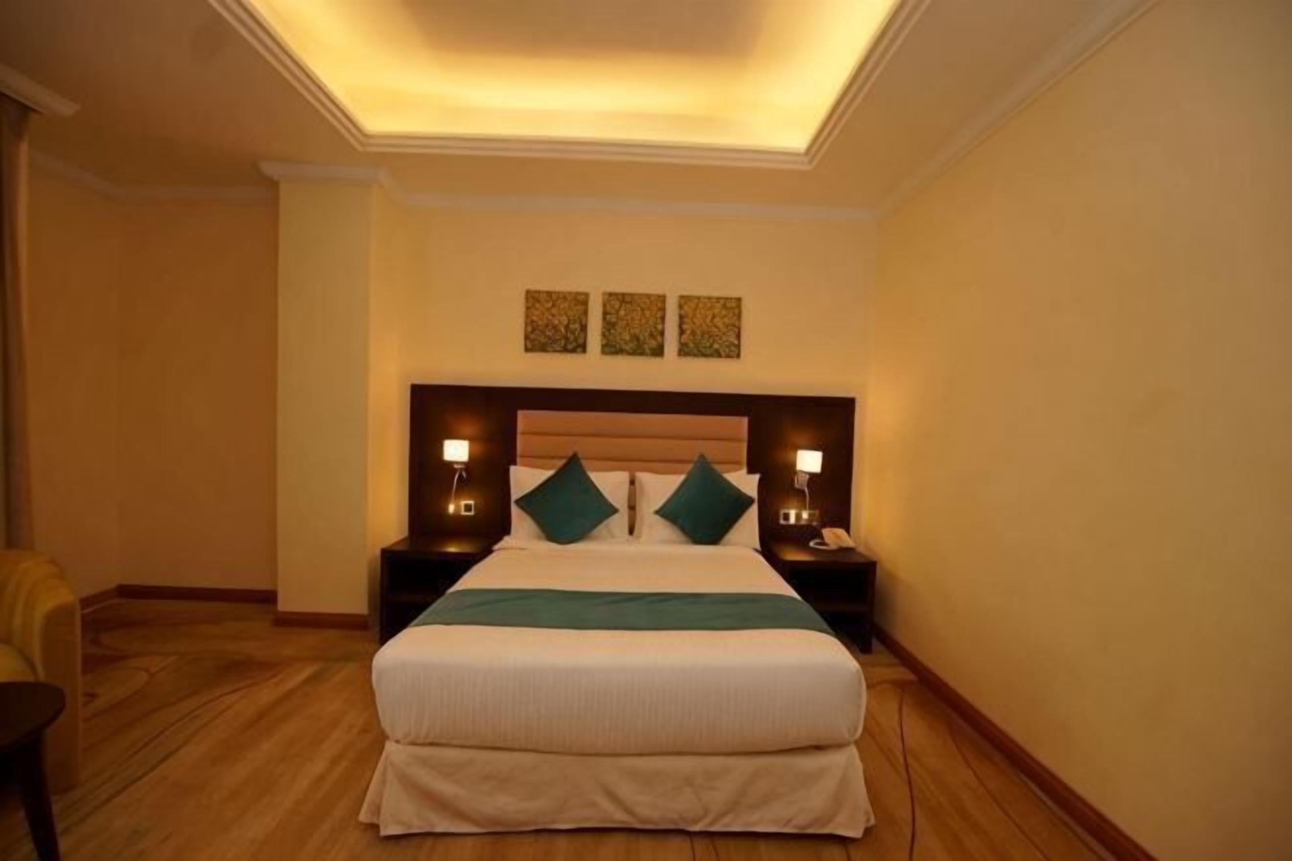 A hotel room with a bed, two bedside tables, a nightstand, a chair, and a ceiling light.