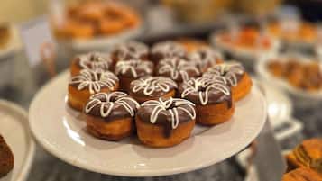 A plate of chocolate-glazed donuts with white icing on a white plate.