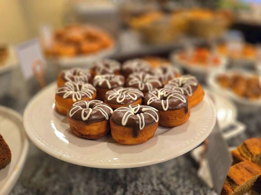 A plate of chocolate-glazed donuts with white icing on a white plate.