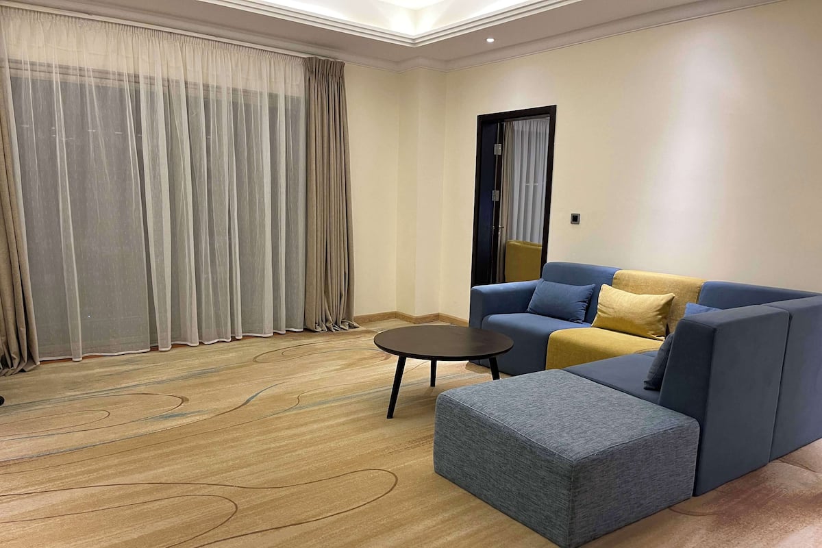 A modern living room with a sectional sofa, a round coffee table, and a patterned carpet.