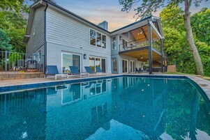 Una casa moderna de dos pisos con piscina, ventanas amplias y un balcón.