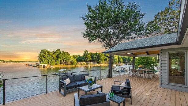 A deck with outdoor seating, overlooking a body of water and trees. - Lakeshore Adrift (Denver)