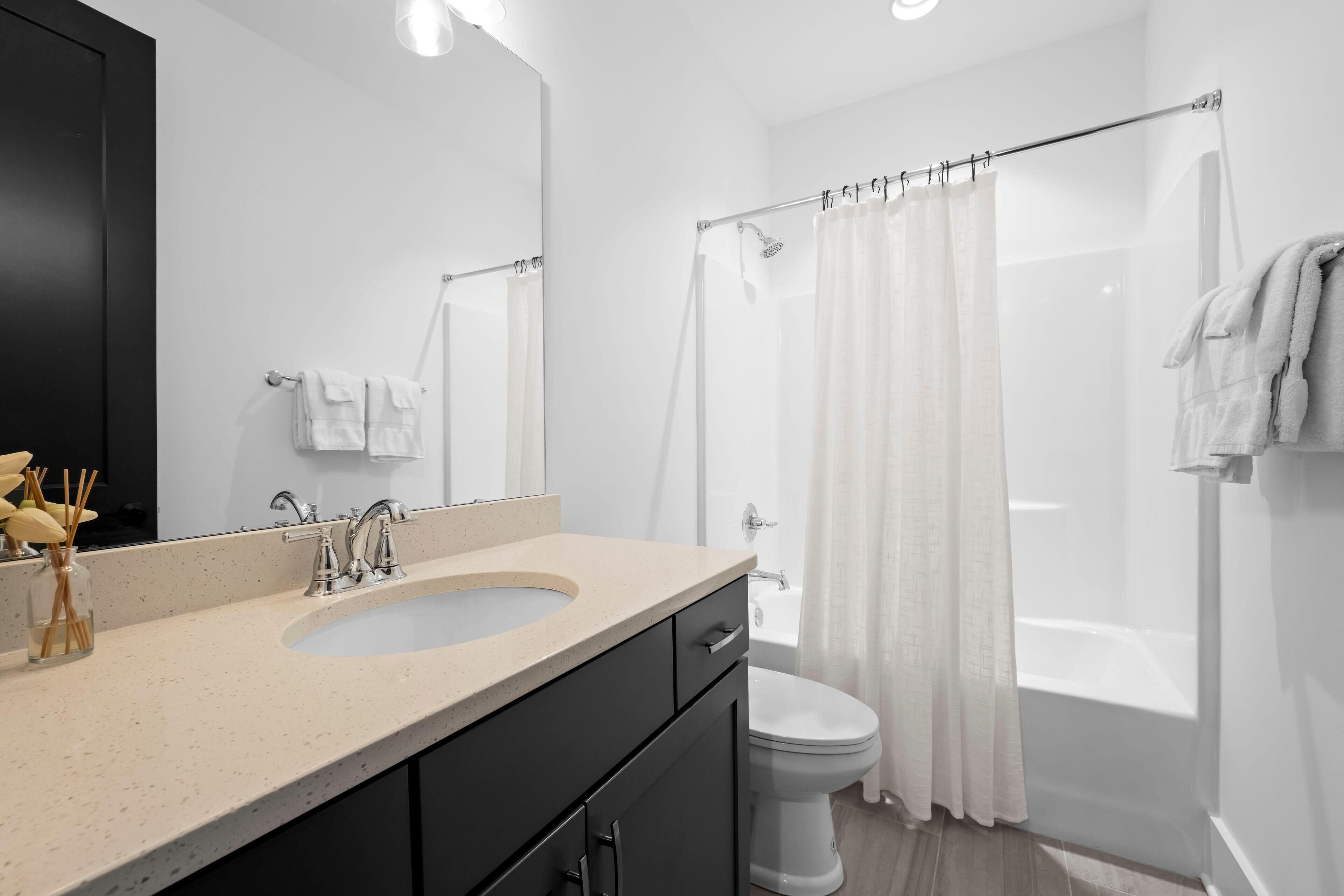 A modern bathroom with a sink, mirror, toilet, and shower area.