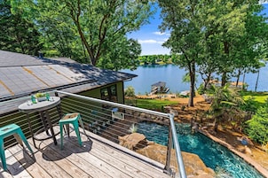 Terraza con mesa y sillas con vista a una piscina y un lago.