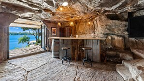 Un rústico espacio de bar con paredes de piedra, taburetes de madera y vistas al mar.