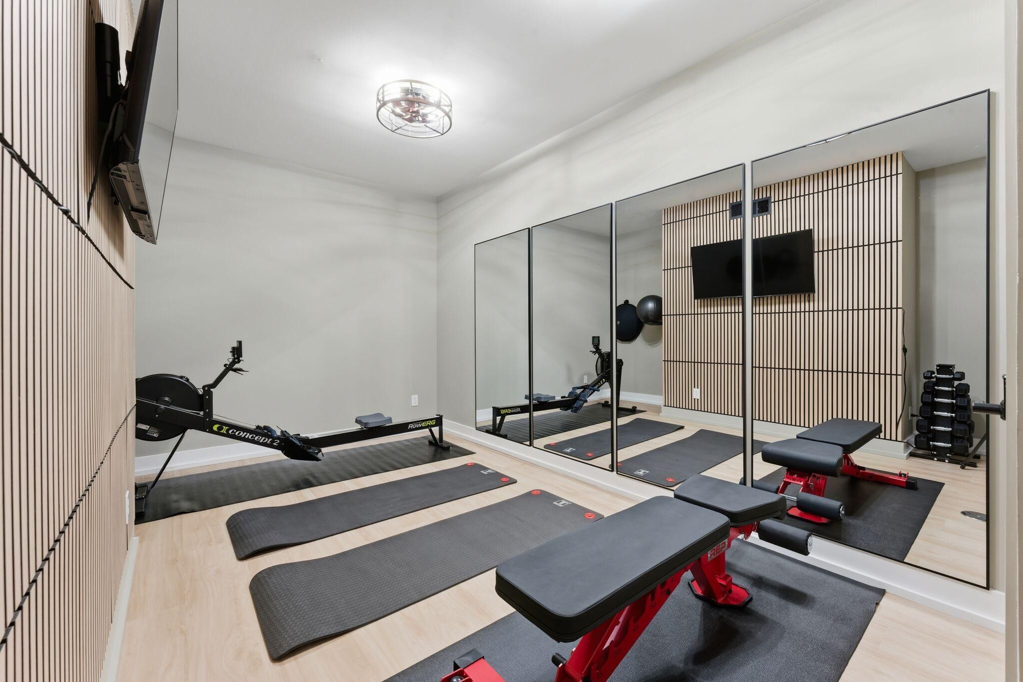 A gym with exercise equipment, mirrors, and black mats.