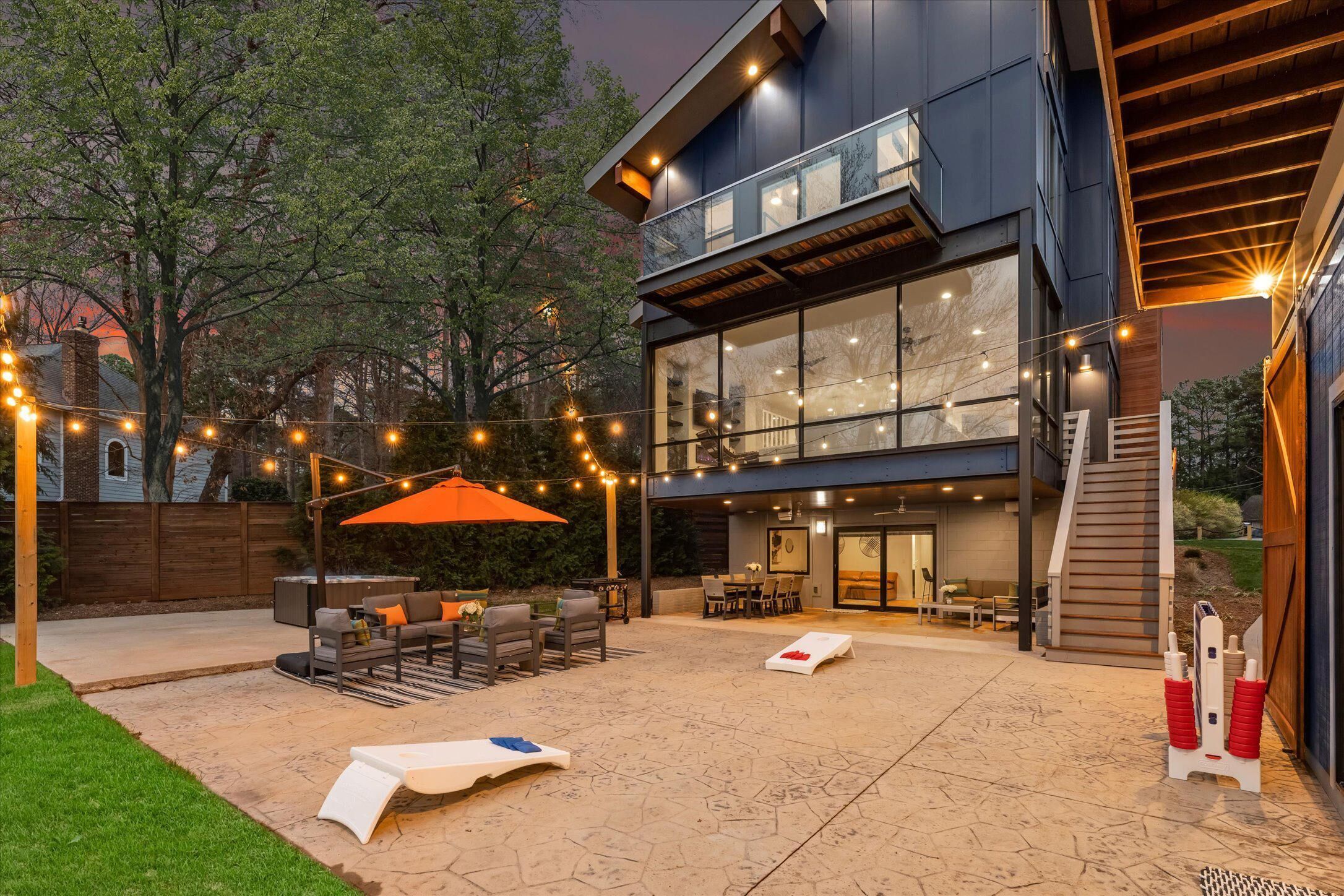 A modern house with a patio area featuring outdoor furniture and string lights.