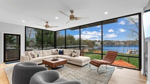 A modern living room with a large window, a sectional sofa, a coffee table, and a brown leather chair.