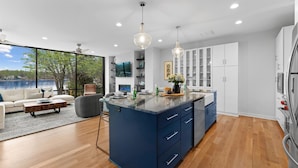 A modern kitchen with a blue island, white cabinets, and pendant lighting.