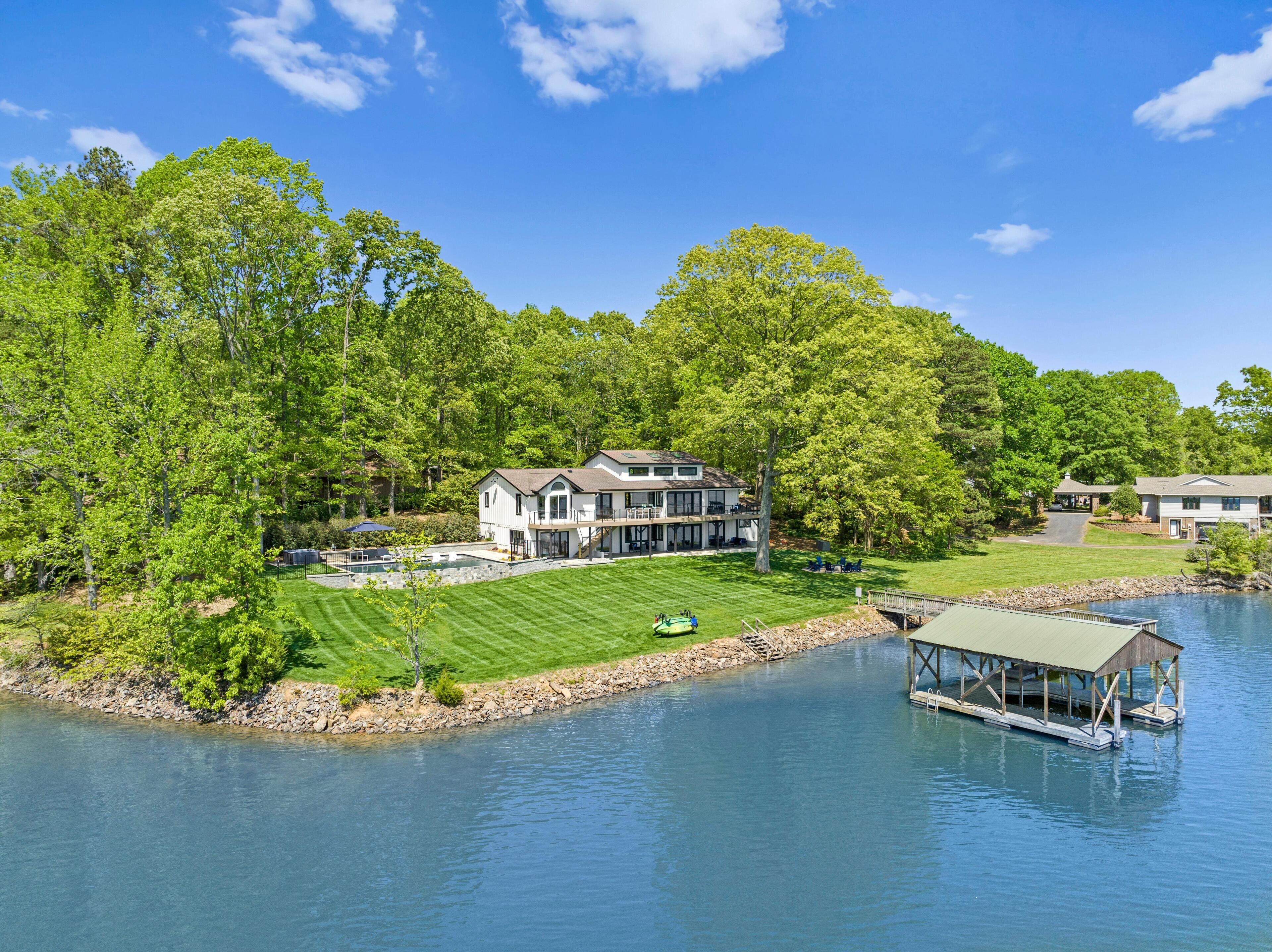 A lakeside property with a large house, a dock, and a well-maintained lawn.
