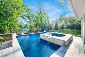 A swimming pool with a hot tub, surrounded by trees and a fence. - Barefoot on Blarney (Mooresville)