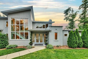 A modern two-story house with a large front window, a visible staircase, and a well-maintained lawn. - Barefoot on Blarney (Mooresville)