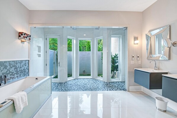 A modern bathroom with a glass-enclosed shower, a large bathtub, and a vanity with a mirror. - Barefoot on Blarney (Mooresville)