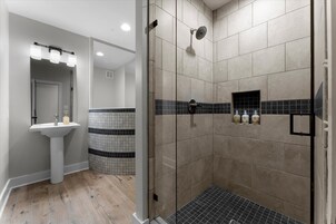A modern bathroom with a shower, a sink, and a mirror with lights.