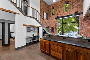 Una cocina moderna con una isla grande, armarios de madera y una pared de ladrillo.