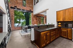 Una cocina moderna con una isla grande, armarios de madera y una pared de ladrillo.