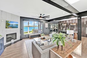 A modern living room with a large window overlooking a lake, a fireplace, and a dining area with a wooden table and chairs.