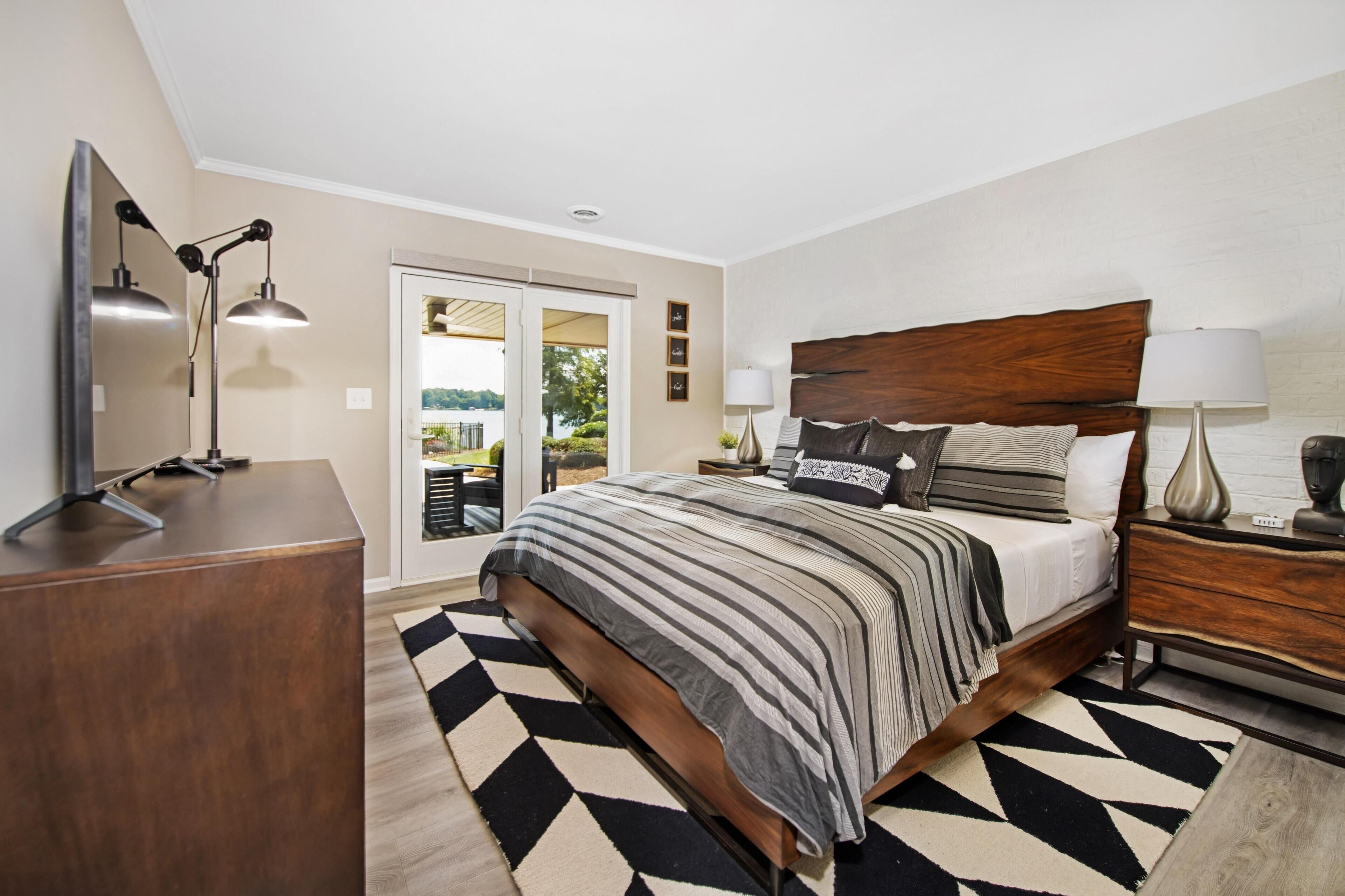 A bedroom with a bed, bedside tables, a desk, and a view of the outdoors.