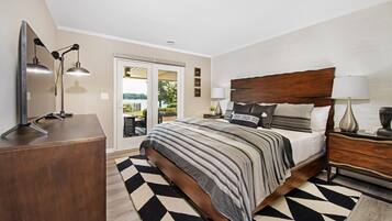 A bedroom with a bed, bedside tables, a desk, and a view of the outdoors.