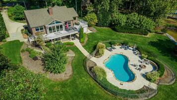 A large house with a swimming pool, a covered patio, and a well-maintained lawn.