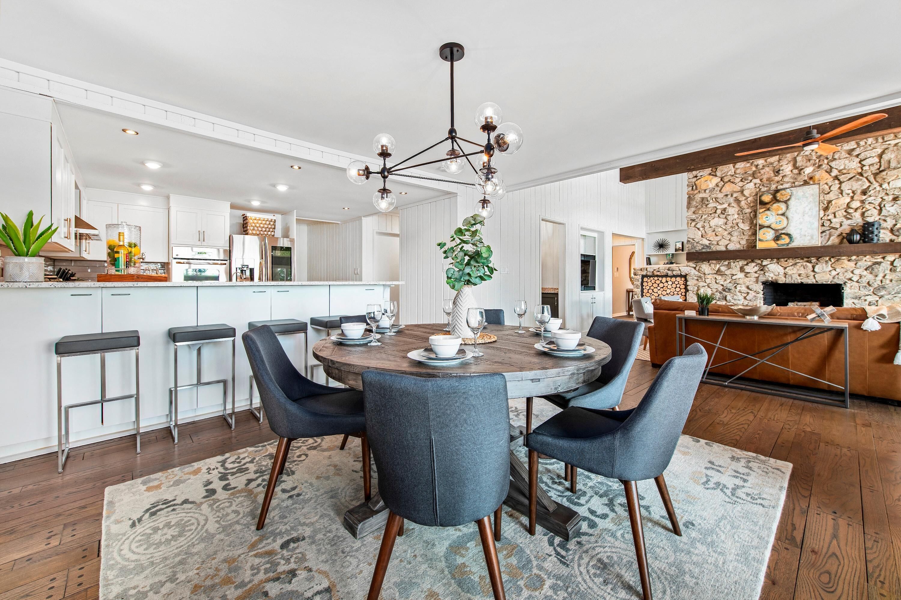A modern kitchen with a central island, bar stools, and a dining area with a round table and chairs.