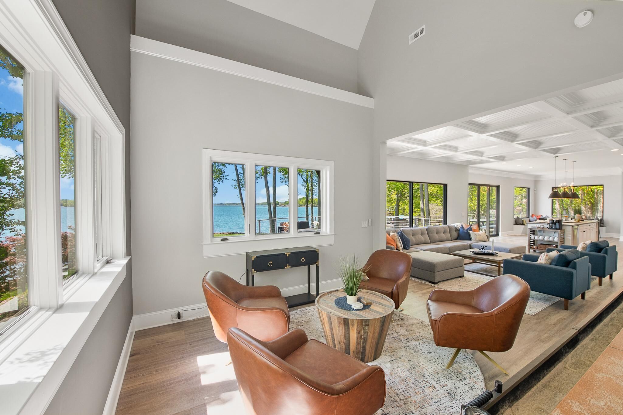 Un salon spacieux, doté de fauteuils en cuir, d’une table basse et offrant une vue sur la mer grâce à de grandes fenêtres.